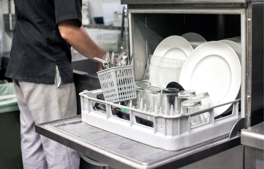 Commercial dishwasher being loading in a commercial kitchen Commercial dishwasher being loading in a commercial kitchen